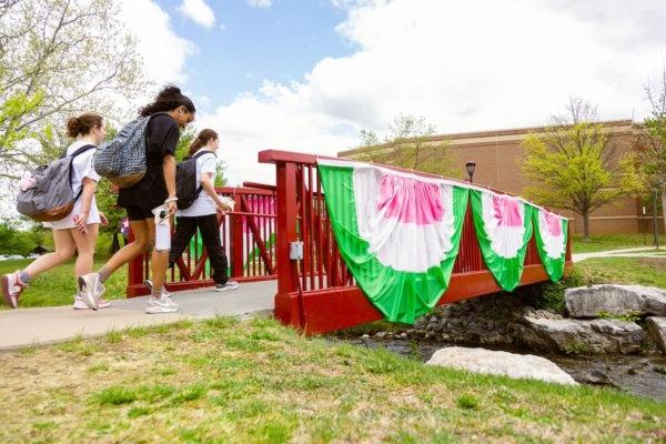 雪兰多的学生走过一座装饰着粉红色、白色和绿色彩绘的桥.